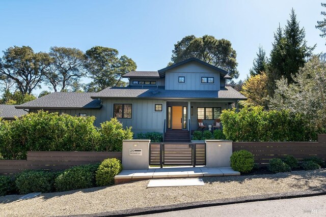 view of front facade featuring board and batten siding, a shingled roof, a fenced front yard, a porch, and a gate