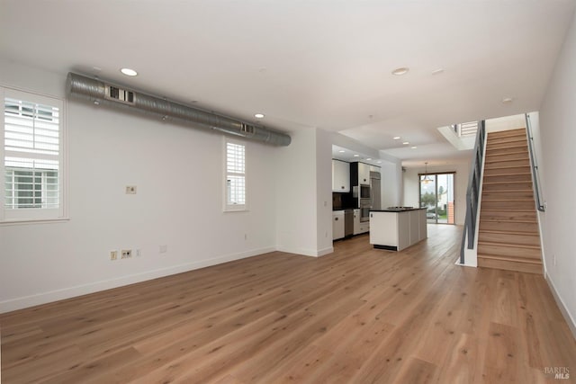 unfurnished living room with visible vents, recessed lighting, stairway, light wood-style floors, and baseboards