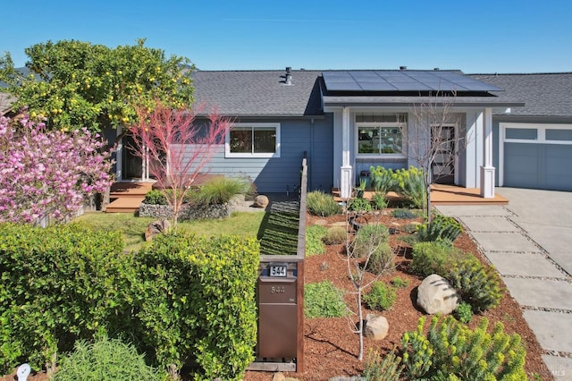 view of front of property with solar panels and roof with shingles