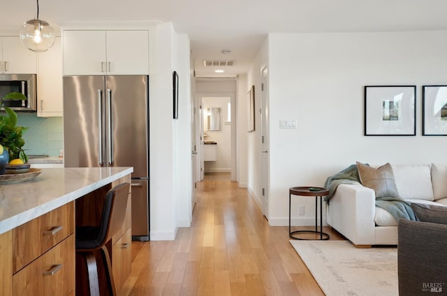 kitchen with visible vents, tasteful backsplash, open floor plan, stainless steel appliances, and light wood-style floors