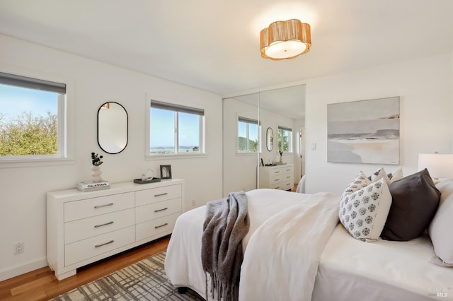 bedroom featuring wood finished floors, baseboards, and a closet