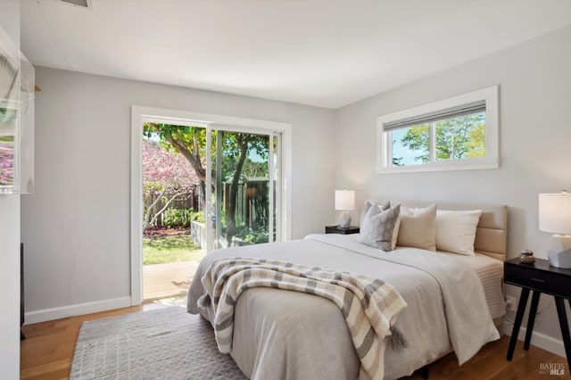 bedroom featuring access to exterior, baseboards, and wood finished floors