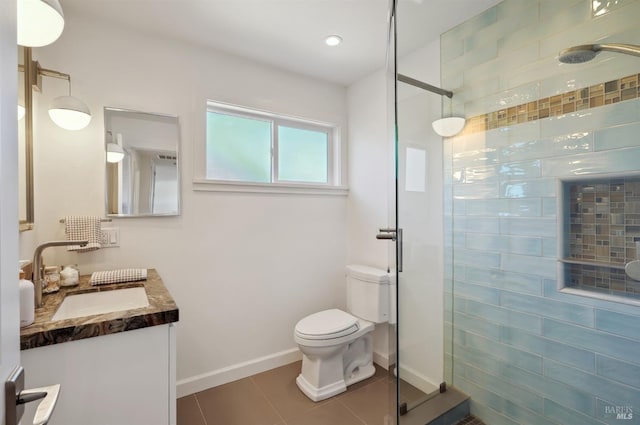 bathroom with baseboards, toilet, a tile shower, tile patterned floors, and vanity