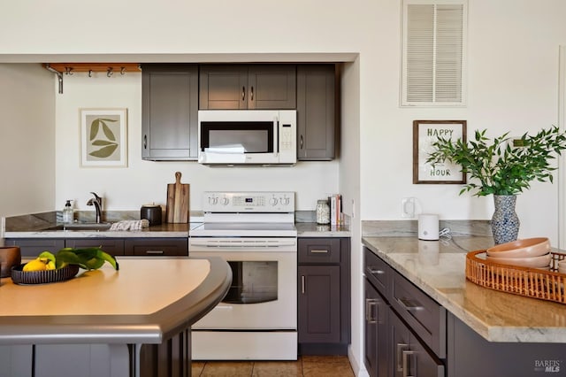 kitchen featuring white appliances, light stone counters, light tile patterned floors, visible vents, and a sink