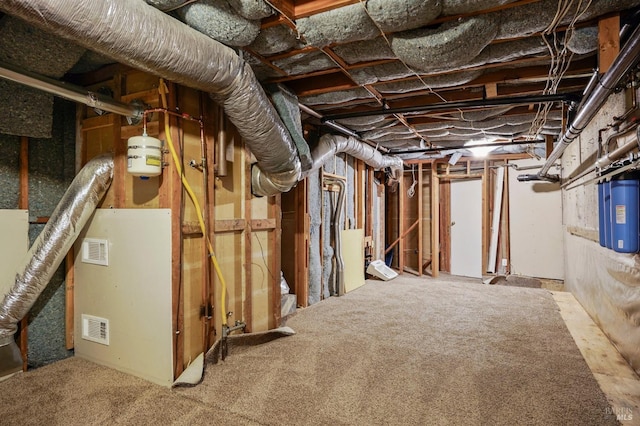 unfinished basement with water heater and visible vents