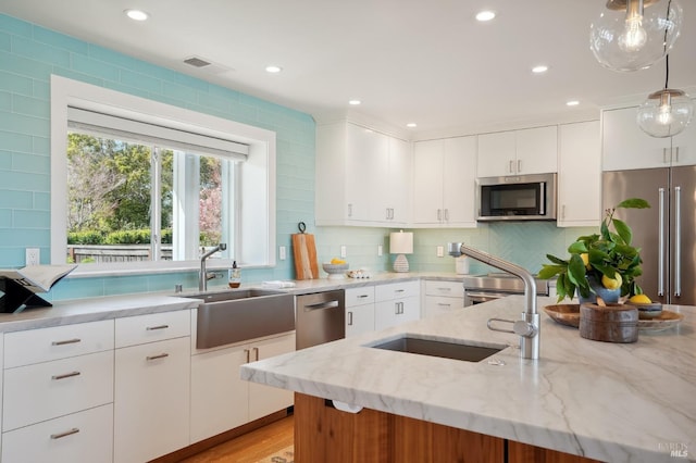 kitchen featuring visible vents, appliances with stainless steel finishes, white cabinetry, and a sink