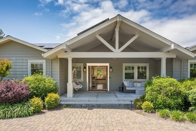 doorway to property featuring roof mounted solar panels and covered porch