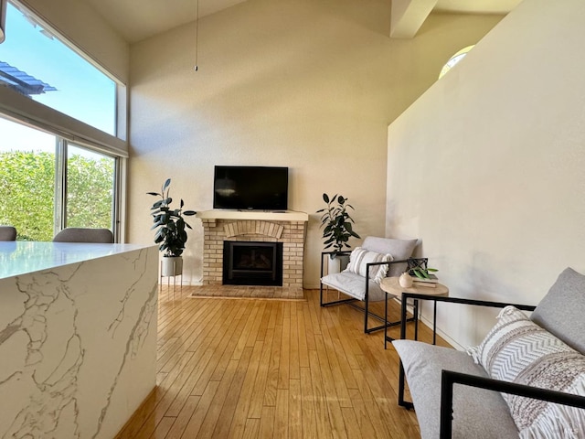 living area featuring a fireplace, a high ceiling, and hardwood / wood-style flooring