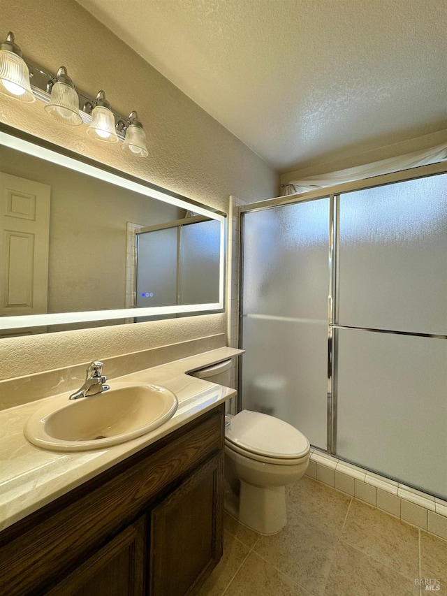 bathroom featuring a shower stall, toilet, vanity, tile patterned floors, and a textured ceiling