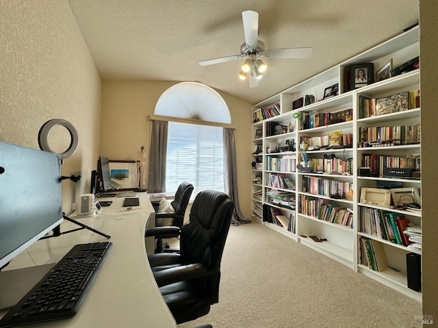 carpeted office space with a textured ceiling, a ceiling fan, and a textured wall