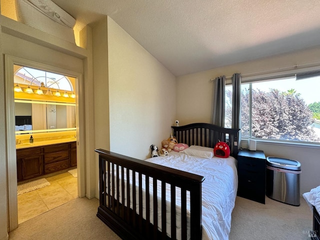 bedroom with ensuite bath, lofted ceiling, a textured ceiling, and light carpet