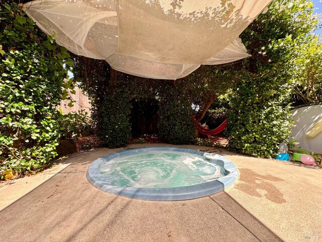 view of pool featuring fence and an indoor hot tub