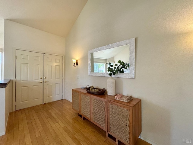 entrance foyer with light wood-style flooring and vaulted ceiling