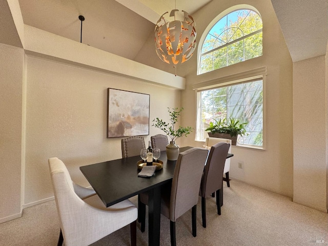 dining room featuring a chandelier, high vaulted ceiling, and light carpet