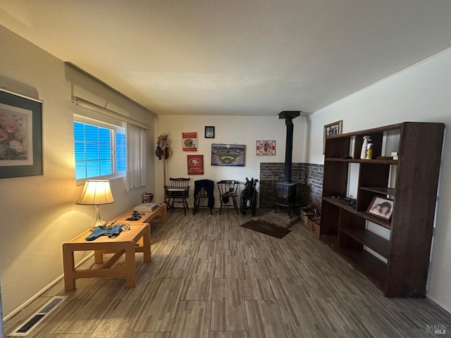interior space with visible vents, wood finished floors, and a wood stove