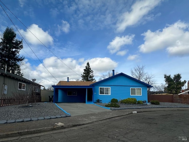 ranch-style home with a carport, concrete driveway, and fence