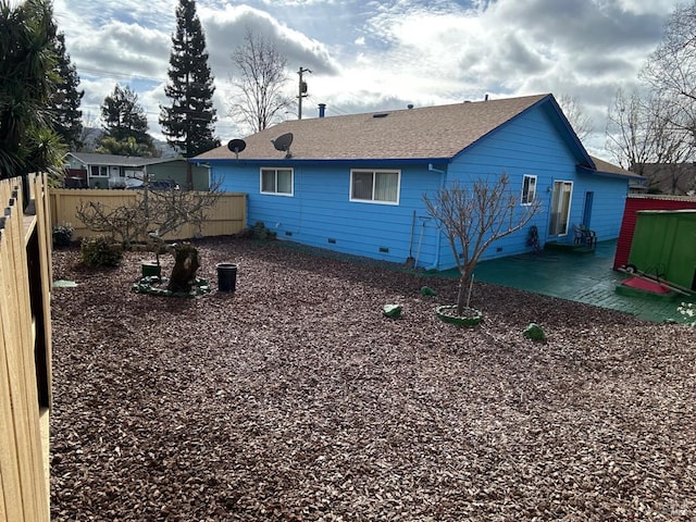 back of house featuring crawl space, a patio, roof with shingles, and fence