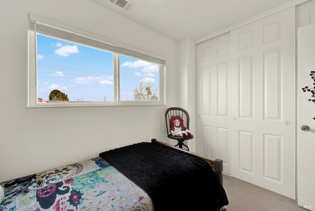 bedroom with a closet, light colored carpet, and visible vents