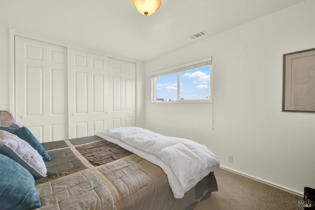 carpeted bedroom with visible vents, a closet, and baseboards