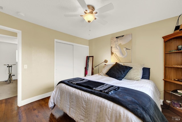 bedroom with visible vents, a closet, baseboards, a ceiling fan, and wood finished floors