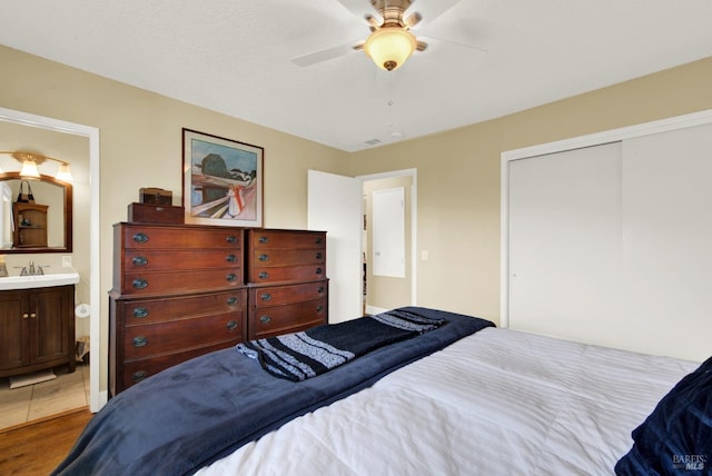 bedroom featuring ensuite bathroom, a closet, a sink, and a ceiling fan