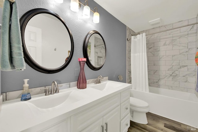 full bathroom featuring double vanity, shower / bath combo, toilet, a sink, and wood finished floors