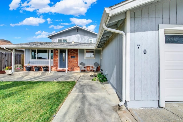 entrance to property with a porch, fence, and a lawn