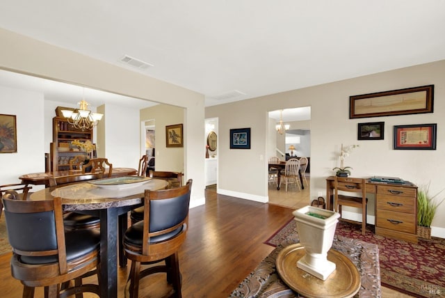 dining space featuring a chandelier, wood finished floors, baseboards, and visible vents