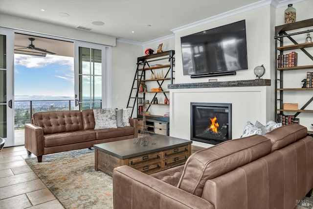 living area featuring crown molding, visible vents, a ceiling fan, and a glass covered fireplace