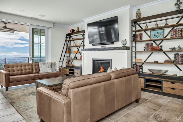 living area with crown molding, a glass covered fireplace, and visible vents