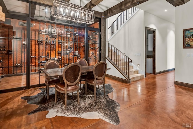 dining area featuring finished concrete floors, stairway, a chandelier, a high ceiling, and baseboards