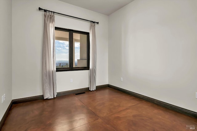 empty room featuring concrete floors, visible vents, and baseboards