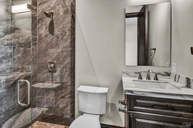 bathroom featuring toilet, vanity, and a stall shower