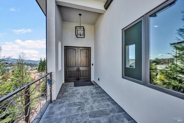 view of exterior entry with a balcony and stucco siding