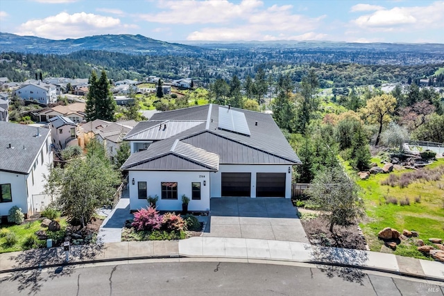 view of front facade with fence, solar panels, an attached garage, a mountain view, and concrete driveway