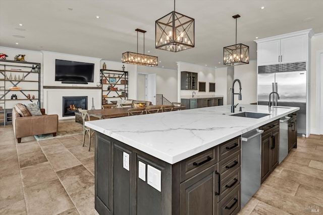 kitchen featuring pendant lighting, a glass covered fireplace, a chandelier, a sink, and open floor plan