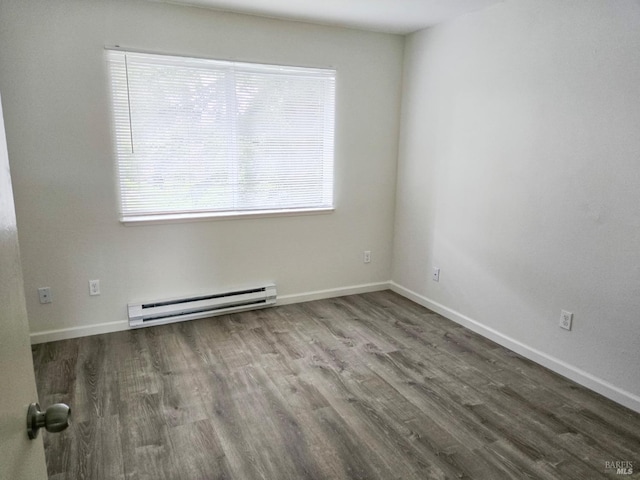 unfurnished room featuring baseboards, wood finished floors, and a baseboard heating unit