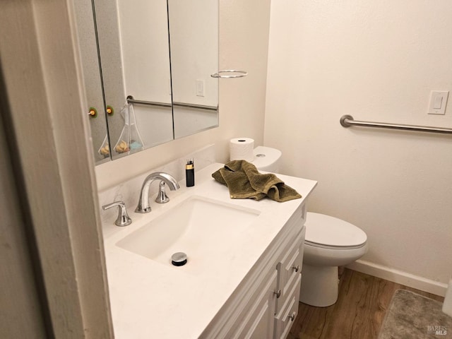 bathroom featuring wood finished floors, toilet, vanity, and baseboards