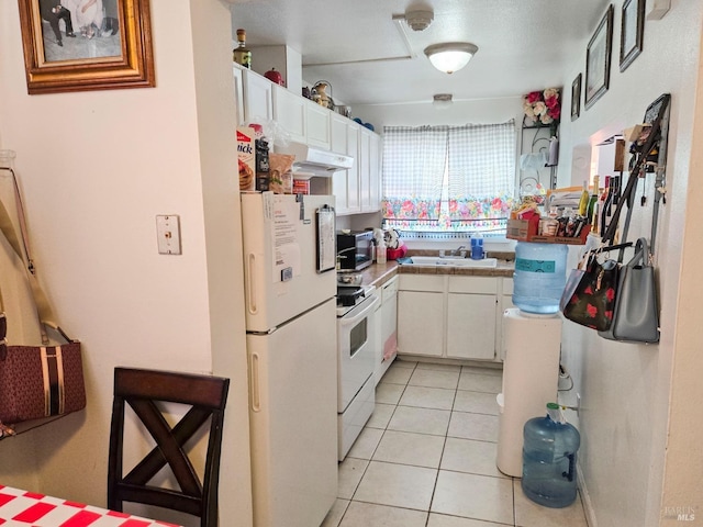 kitchen featuring a sink, under cabinet range hood, light tile patterned flooring, white appliances, and white cabinets