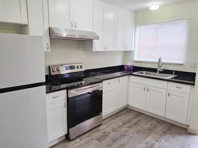 kitchen with white cabinetry, a sink, freestanding refrigerator, under cabinet range hood, and electric stove