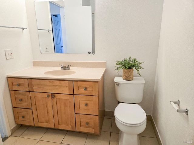 half bathroom with baseboards, tile patterned flooring, vanity, and toilet