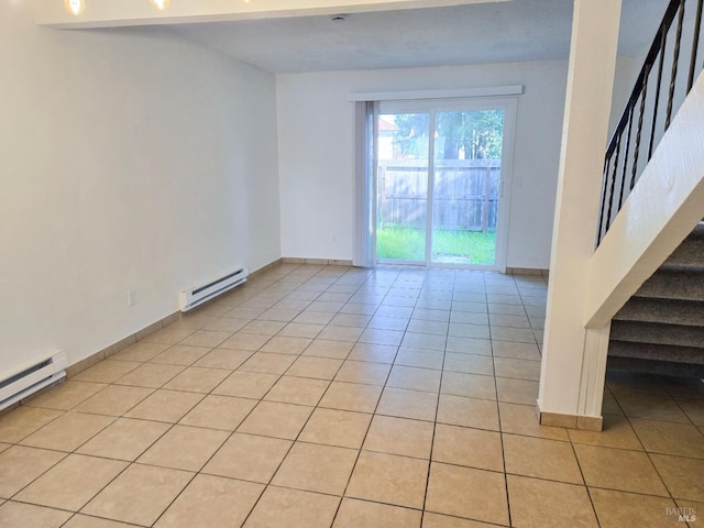 spare room with light tile patterned floors, baseboards, stairway, and a baseboard radiator