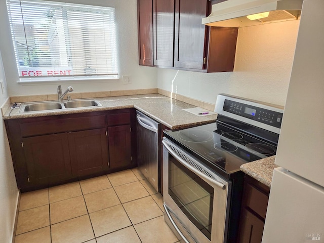 kitchen featuring a sink, appliances with stainless steel finishes, light countertops, under cabinet range hood, and light tile patterned floors
