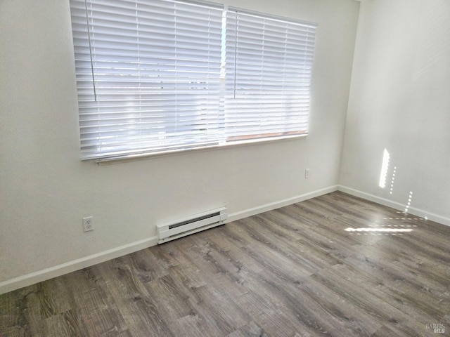 empty room featuring a baseboard radiator, wood finished floors, and baseboards
