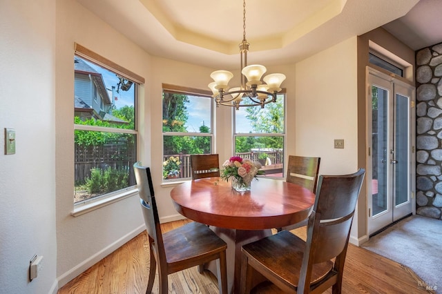 dining room with a tray ceiling, baseboards, a notable chandelier, and wood finished floors