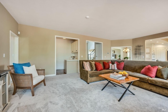 living area with baseboards, light colored carpet, and an inviting chandelier