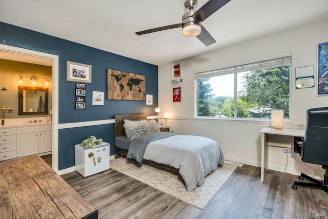 bedroom featuring wood finished floors, baseboards, a ceiling fan, and ensuite bath