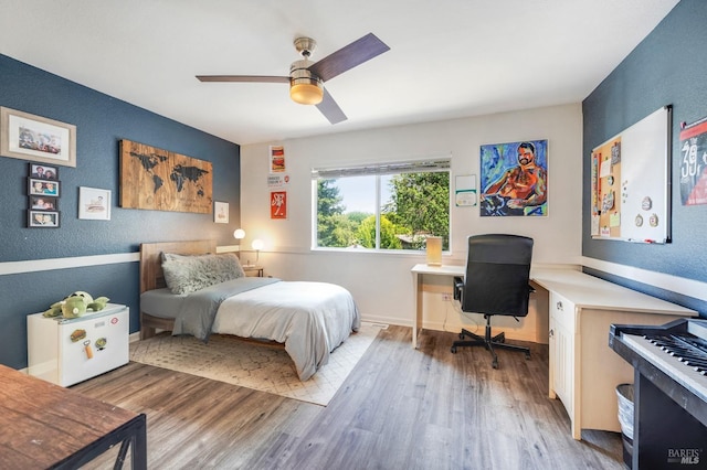 bedroom with a textured wall, ceiling fan, baseboards, and wood finished floors