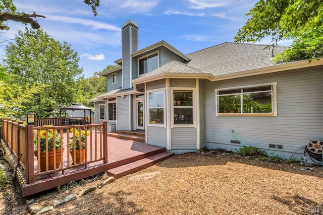 back of house featuring a deck, crawl space, a chimney, and a shingled roof