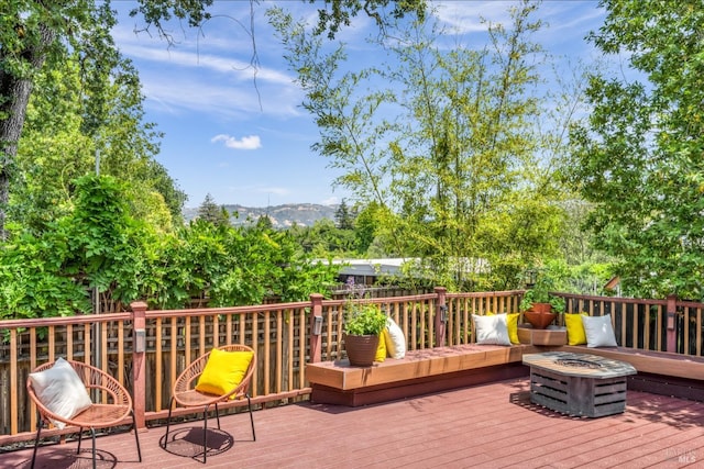 wooden deck featuring a mountain view and an outdoor fire pit